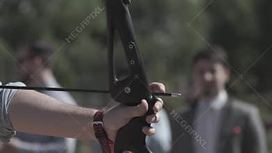 Sportswoman practicing archery. Close up hand of Male Soldier training with the arror and bow