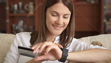 Beautiful woman online banking using smartwatch shopping online with credit card at home lifestyle
