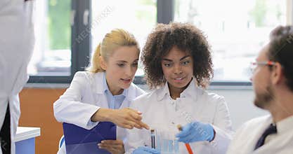 Mix Race Group Of Scientists Analyzing Chemicals In Test Tubes Making Notes About Experiment Working Together In Modern