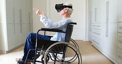 Senior man on wheelchair using vr headset in bedroom