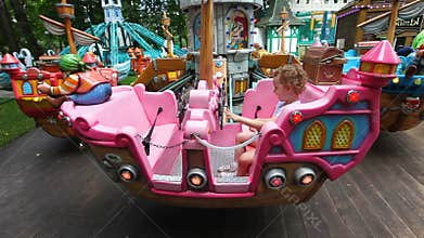 Little girl rides a carousel. Park of attractions