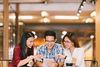 Young Asian college students or coworkers using digital tablet together at coffee shop, diverse group. Casual business, freelance