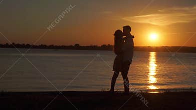 Loving senior couple enjoying a romantic sunset evening dancing together on the beach filmed