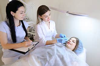 Girl of permanent tattoo artist demonstrates to female student h