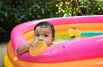 Close up baby boy clutch the edge of kidde pool with nature background