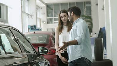 Young couple arguing and choose the car in car dealership