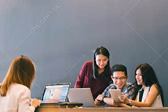 Group of young Asian business colleagues in team casual discussion, startup project business meeting or happy teamwork brainstorm