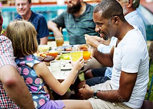 Black man clinking drink with young girl in summer party