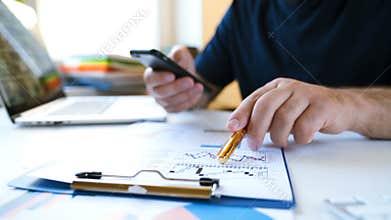 Businessman works with a smartphone and analyzes charts