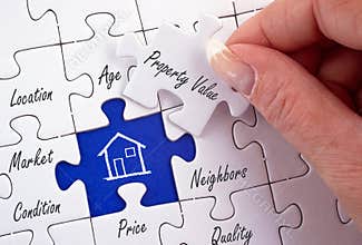 Property Value - female hand with real estate puzzle