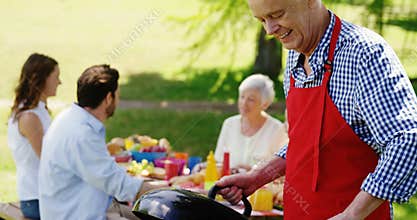 Senior man preparing food on barbecue in the park