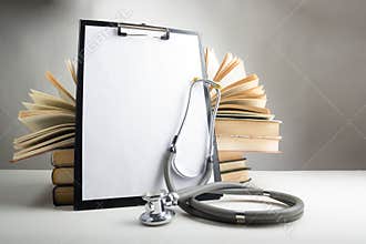 Open hardback books on the table, medical clipboard with blank p