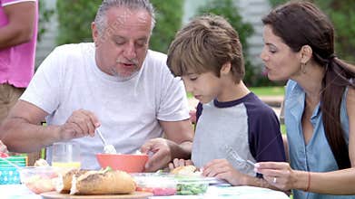 Multi Generation Family Enjoying Meal In Garden Together