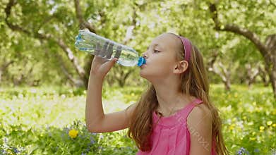 Face of young girl drink water bottle at summer green park