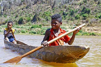 Young Malagasy african boy rowing traditional canoe