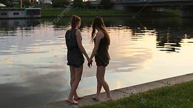 Two girls girlfriend walk along the city waterfront and fun talk.