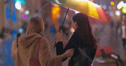 Two women friends meeting in rainy evening