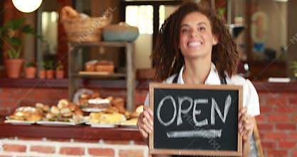Smiling barista holding an open signboard