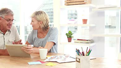 Smiling casual colleagues using digital tablet in office