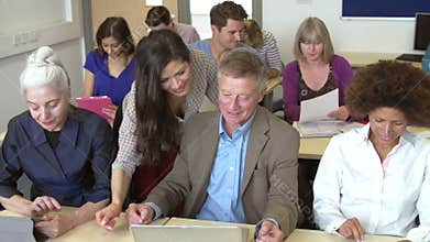 Mature Students In Further Education Class With Teacher