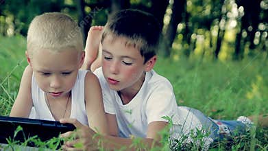 Two boys in white clothes lay on the grass in the