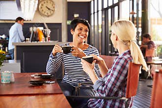Two female friends talking at a coffee shop