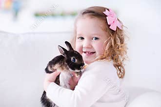 Little girl playing with a real pet rabbit