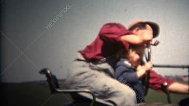 (8mm Vintage) 1952 Man Smoking Pipe Driving Tractor With Child On Lap. Iowa, USA.