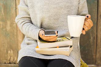 Girl with cell phone, cup of coffee and books
