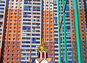 Dome of small church against the big modern building.