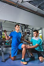 Sport, fitness, teamwork, bodybuilding people concept - man and personal trainer with barbell flexing muscles in gym