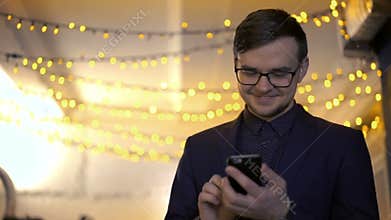 Happy businessman using phone on a background of a lights