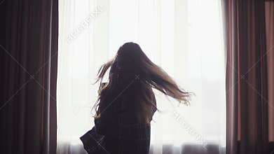 Enthusiastic happy girl listens to the music from smartphone in her hands, spins, dances and makes fun,earphones