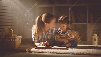 Happy family mother and daughter read a book in evening