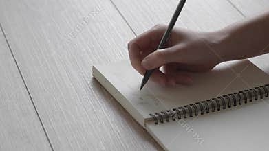 Female hand writes a note in a notebook. A letter to a friend. Poetry in the reflected light.