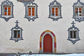 Gothic castle white facade with paintings at windows and red arched door