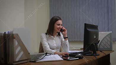 Business woman working on her computer and talking on the phone.