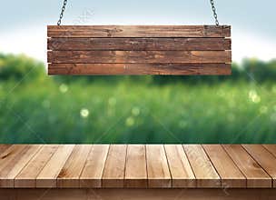Wood table with hanging wooden sign on green nature blurred background