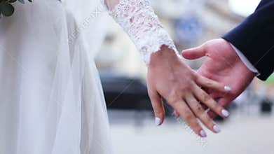 Close up of lovers wedding couple holding hands at the street. slow motion
