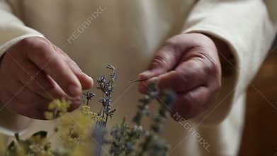 Close up of a monk crushing dry herbs