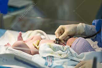 Newborn male baby being checked with stethoscope