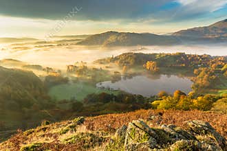 Autumn Fog Lingering Over Loughrigg Tarn In The English Lake District.