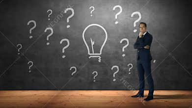 Businessman standing against question marks and bulb