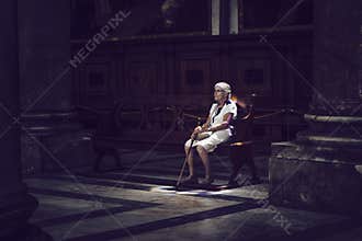 Old woman sitting in colored light on church bench