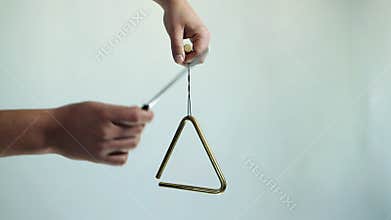 Hands play a musical triangle. Hit a few times