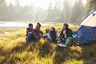 Happy family on a camping trip relaxing by their tent