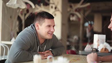 Smiling man cheerfully talking to woman. Lovers have conversation as they sit in some place with good interior design.