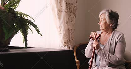 Thoughtful senior woman looking through window