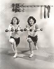 Two women exercising with dumbbells at gym