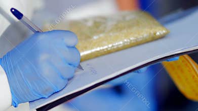 Inspector checks quality of grain in a large warehouse - writes checks to the documents data